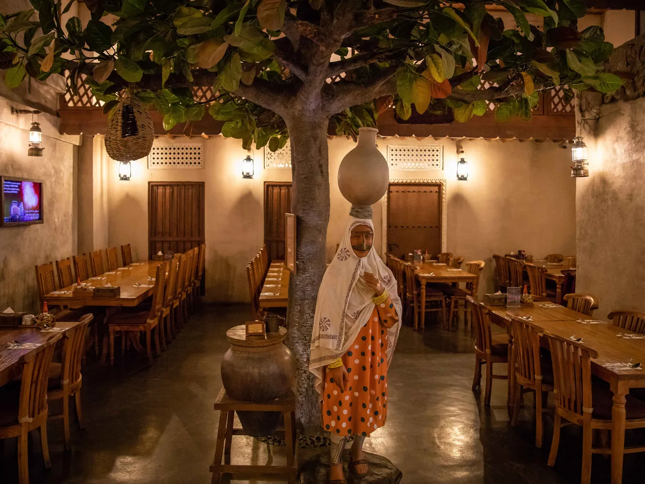 The Dubai Festival City branch: a dining room under a tree, with a statue of a woman in traditional dress carrying a jar